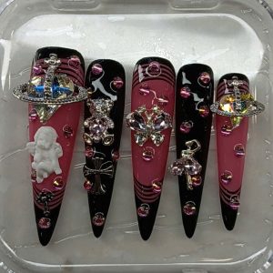 Long stiletto Y2K press-on nails in black and pink featuring 3D planet orb, cherub, cross, and teddy bear charms by Pro Nails